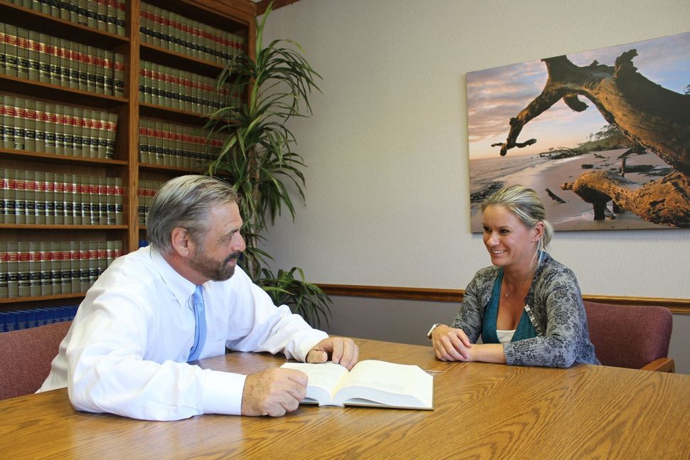 A man and a woman are sitting at a table reading a book.