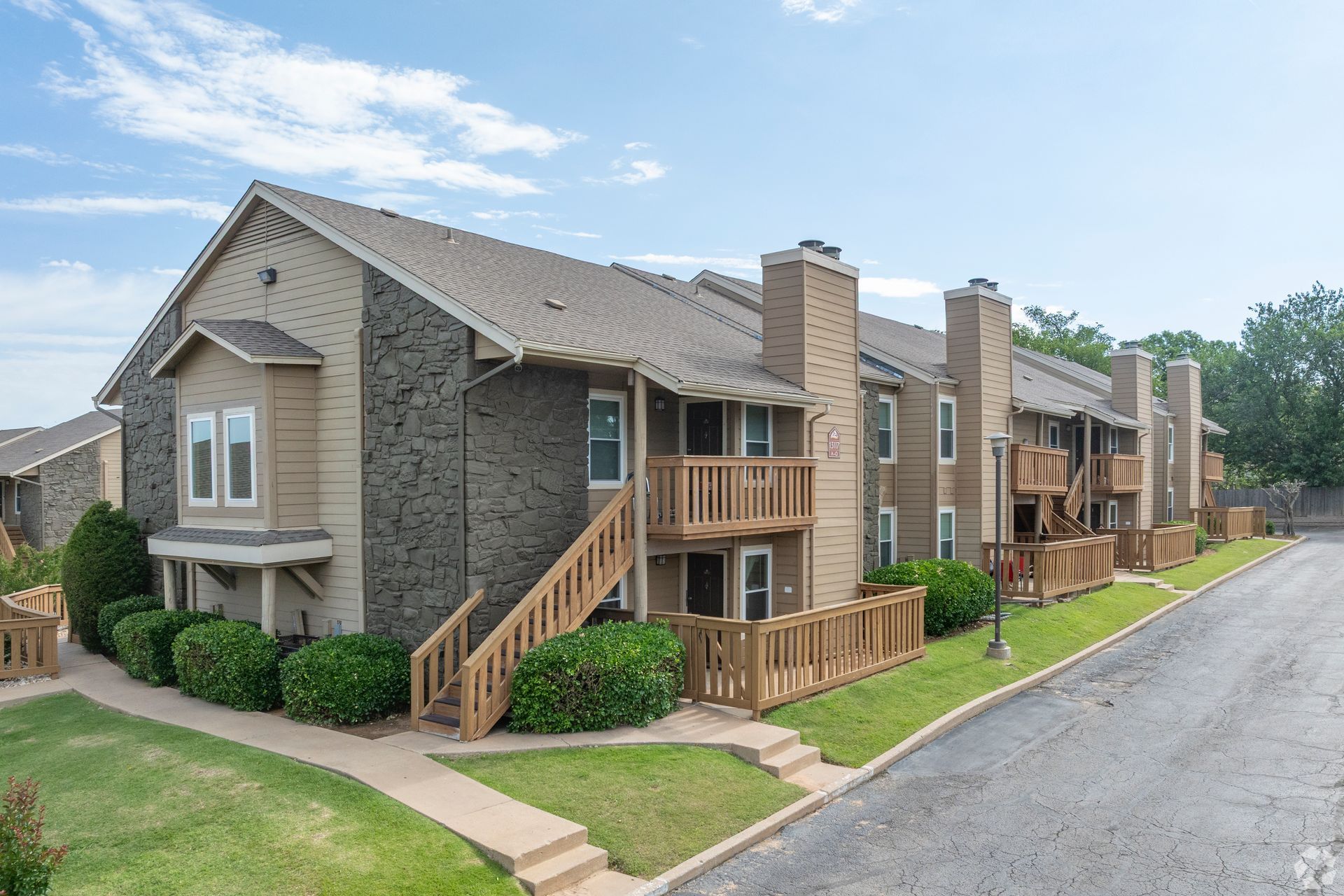 Row of beige and brown apartment buildings beside a paved road on a sunny day