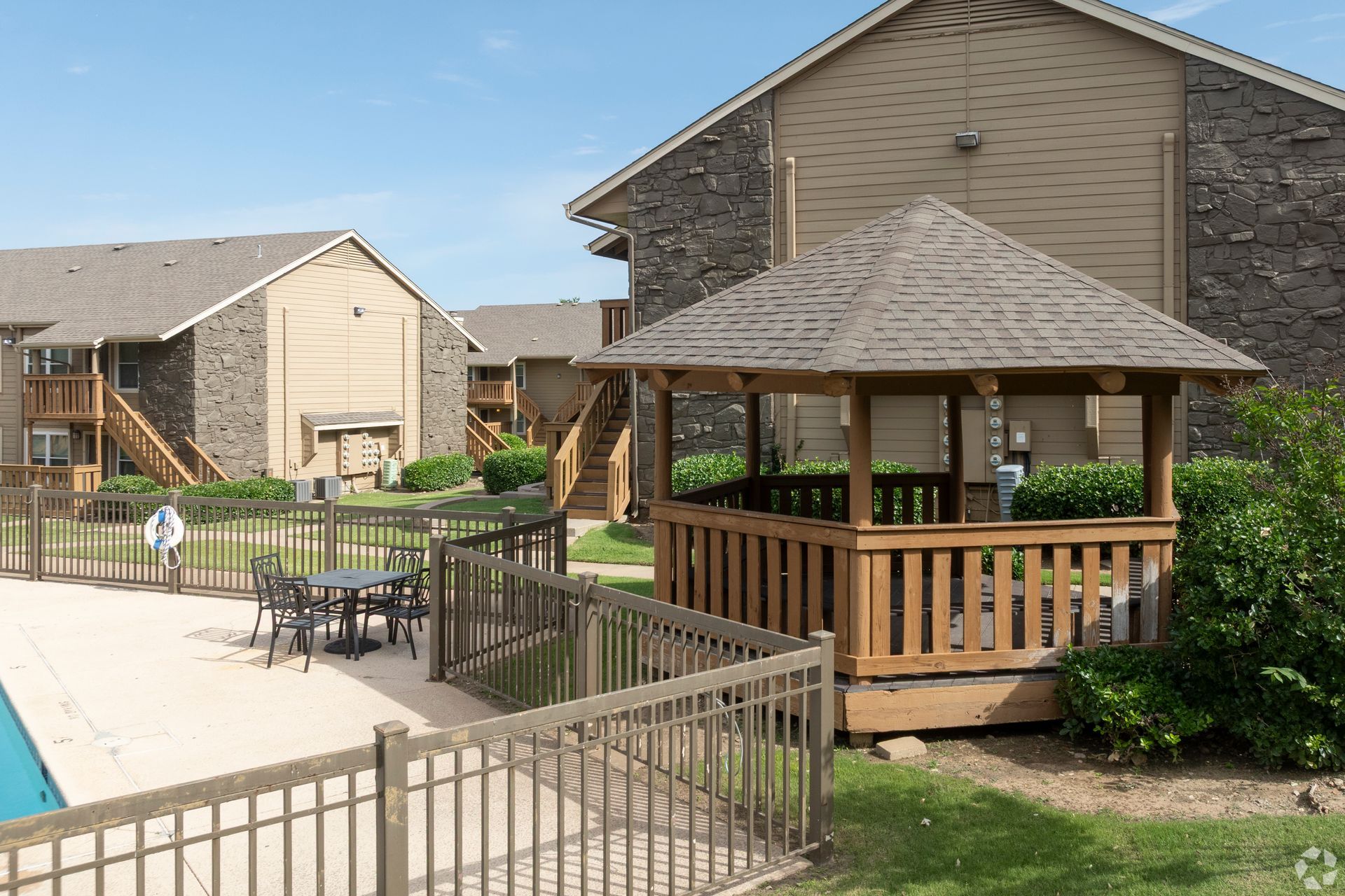 Apartment courtyard with a gazebo beside a pool and fenced patio area