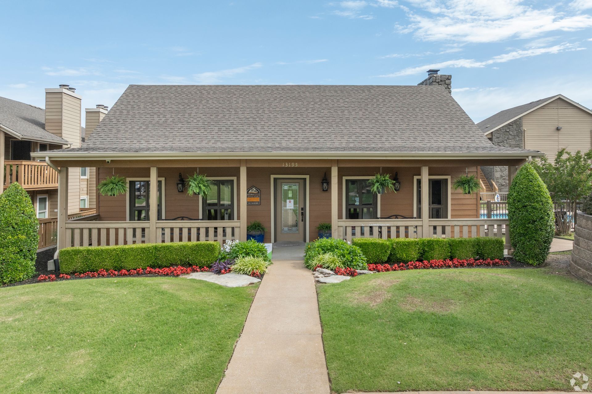 Single-story house with a front porch, centered walkway, and neatly trimmed lawn and flower beds.