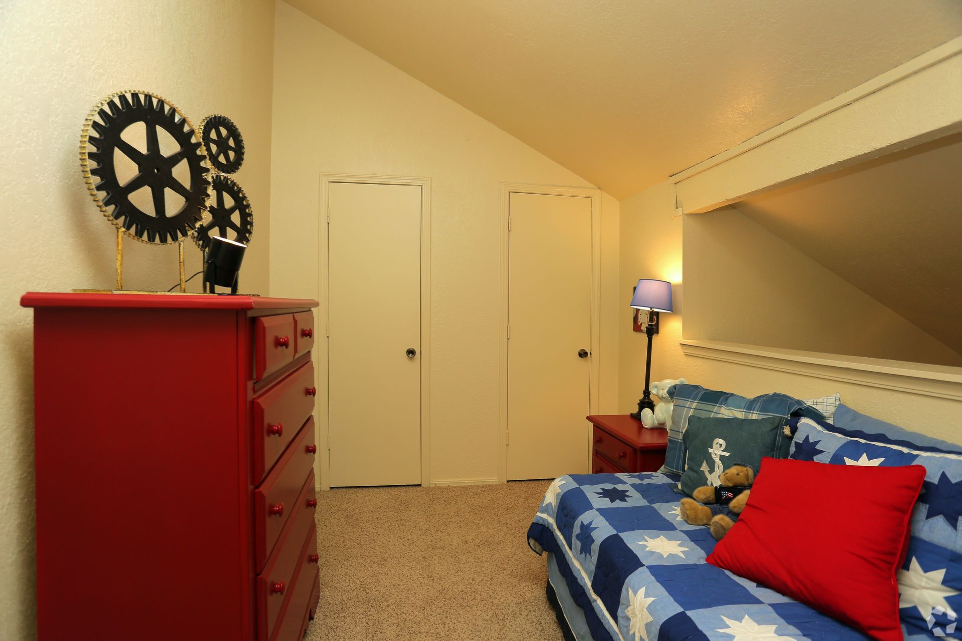 Bedroom with red dresser, blue bed, and decorative gears on the wall