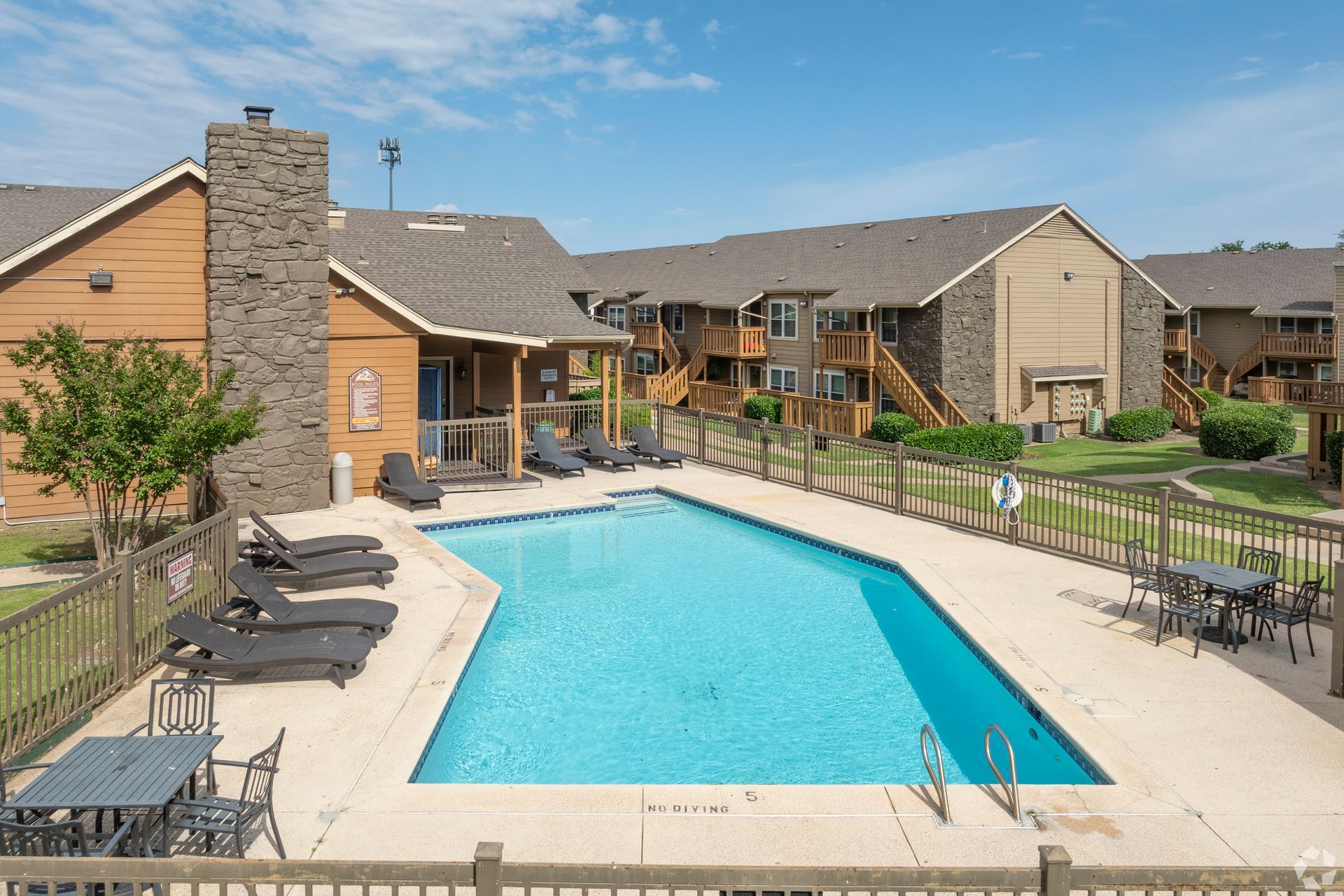 Apartment pool courtyard with turquoise water, lounge chairs, and surrounding brick buildings