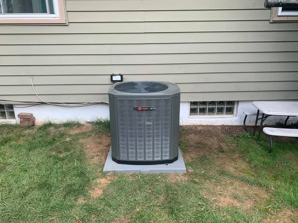 A man is working on an air conditioner on the side of a building.