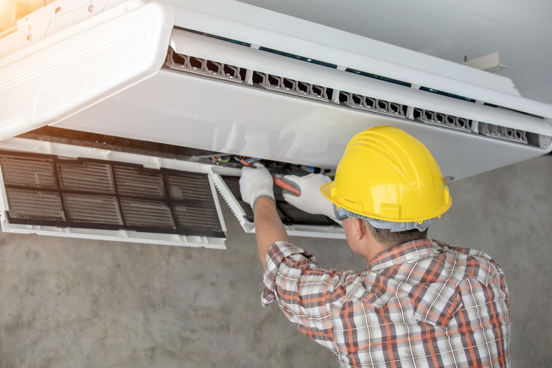 An air conditioning repair contractor repairing a home AC system using professional tools.