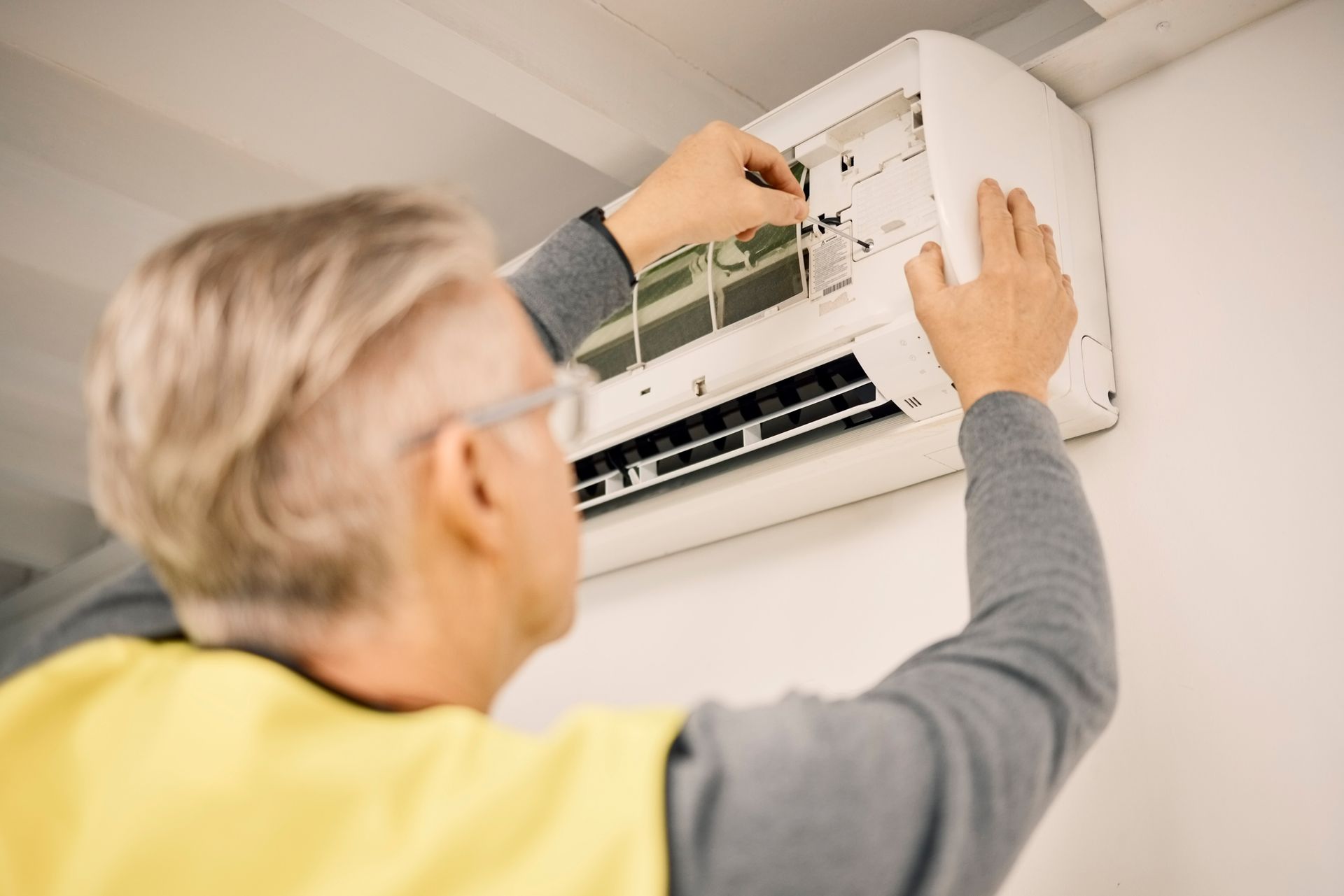 Person repairing a wall-mounted air conditioner unit.
