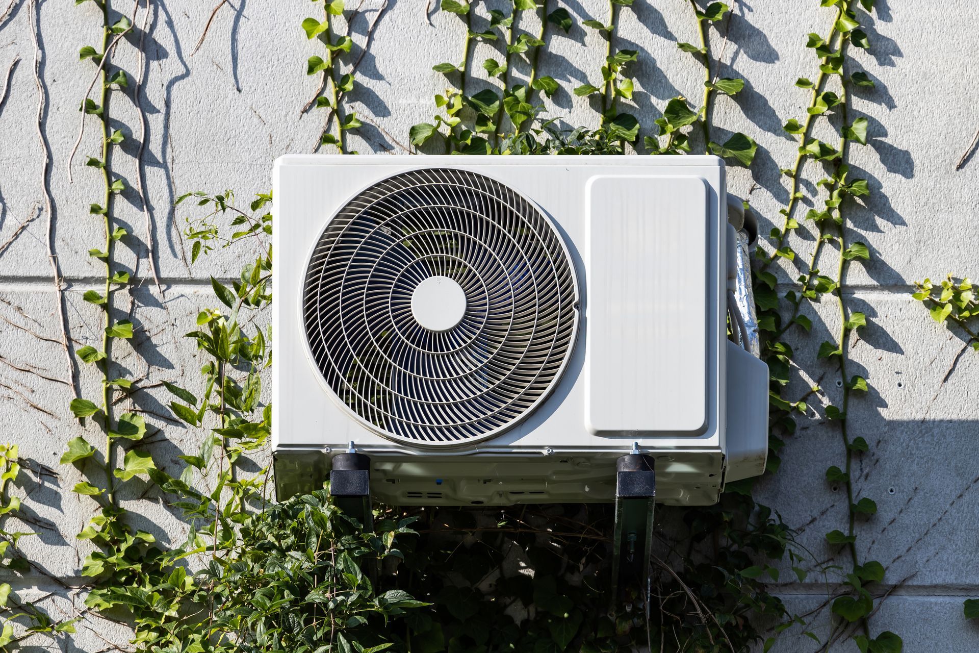 A white air conditioner is mounted on the side of a building.