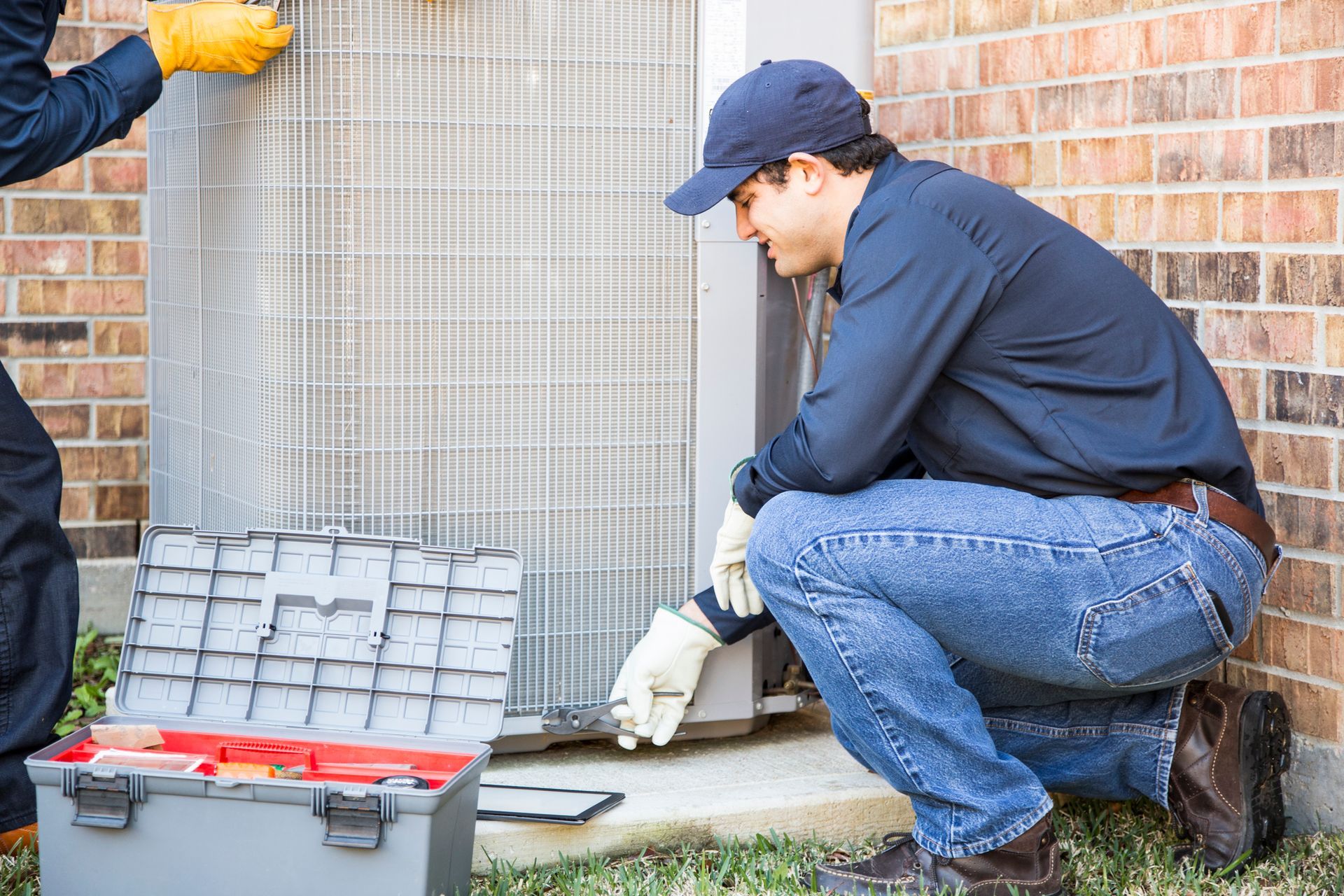 Air conditioning repair contractors performing maintenance on an outdoor AC unit.