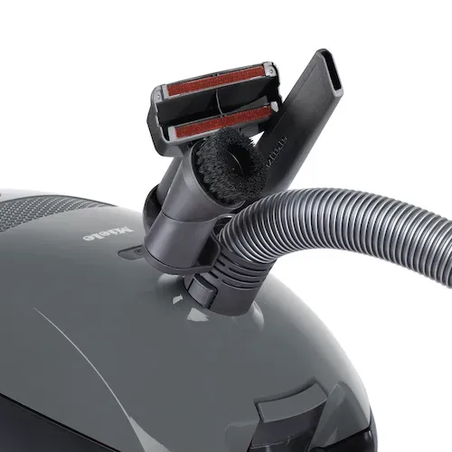 Gray Miele vacuum cleaner with a hose, wand, and floor brush, on a white background.