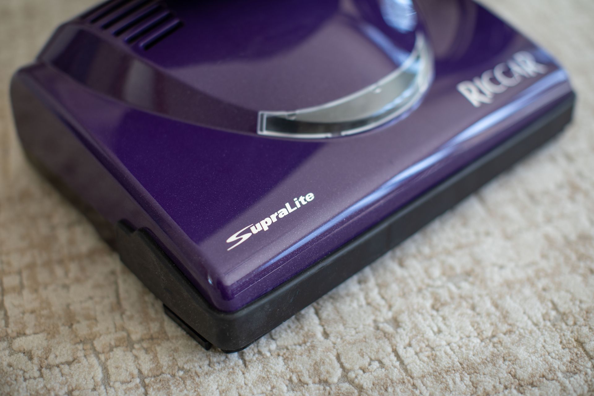 Black and purple upright vacuum cleaner with a long handle and a light on the base.