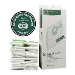 Stack of vacuum cleaner bags, a box of bags, and a green circle logo. White bags. Green logo and text on box.