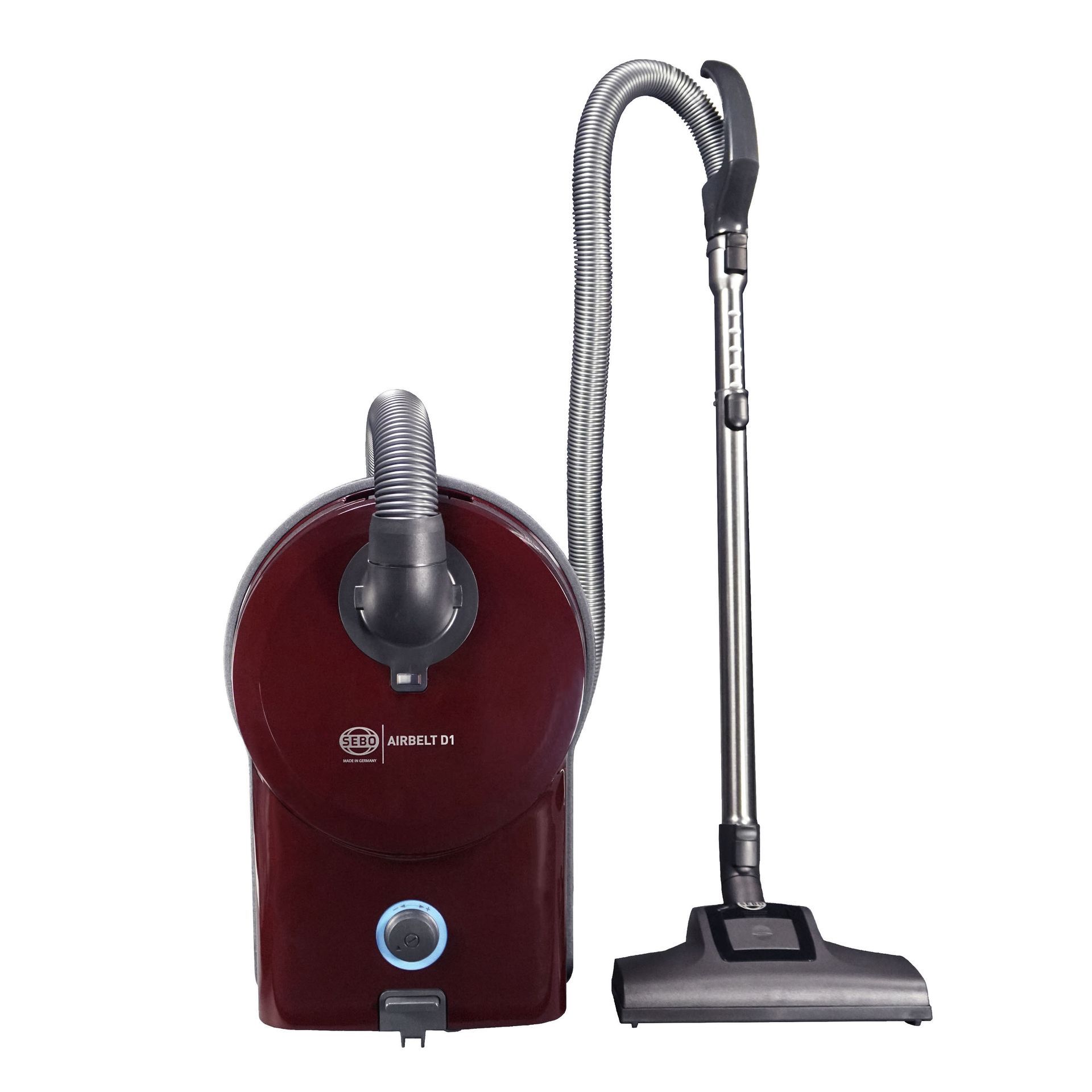 Red canister vacuum cleaner with silver hose and wand, nozzle on floor.