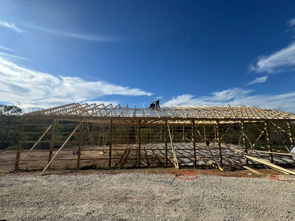 Construction of a wooden building frame against a blue sky, workers on the roof.