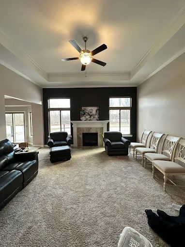 Spacious living room with a fireplace, dark accent wall, and beige carpet.