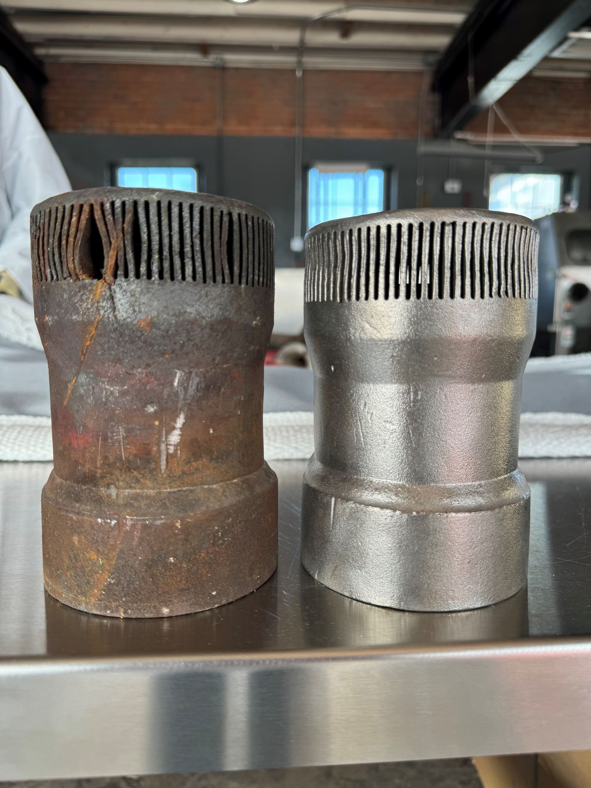 Two pieces of metal are sitting on a stainless steel table.