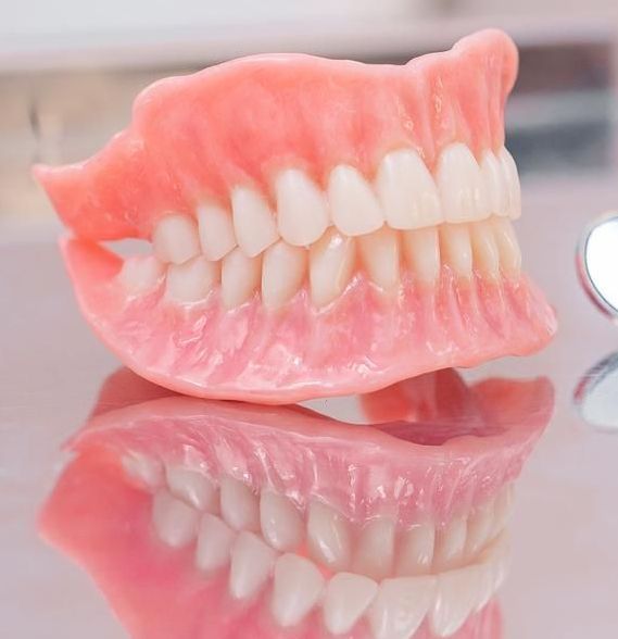 Denture is Sitting on Top of a Mirror on a Table — Cosmetic Denture Services–Jacob Maxwell in Sarina, QLD