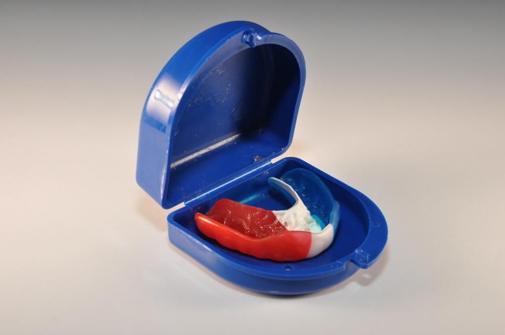 A Red White and Blue Mouth Guard Is in A Blue Case — Cosmetic Denture Services–Jacob Maxwell in Moranbah, QLD