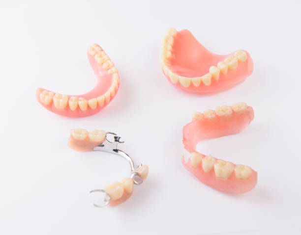 Group of Dentures Sitting on Top of Each Other on a White Surface — Cosmetic Denture Services–Jacob Maxwell in Mackay, QLD