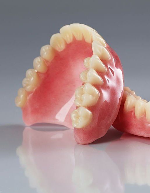 Pair of Dentures Are Sitting on Top of Each Other on a Table — Cosmetic Denture Services–Jacob Maxwell in Mackay, QLD