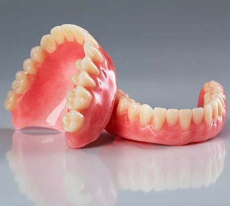 Pair of Dentures Are Sitting on Top of Each Other on a Table — Cosmetic Denture Services–Jacob Maxwell in Mackay, QLD