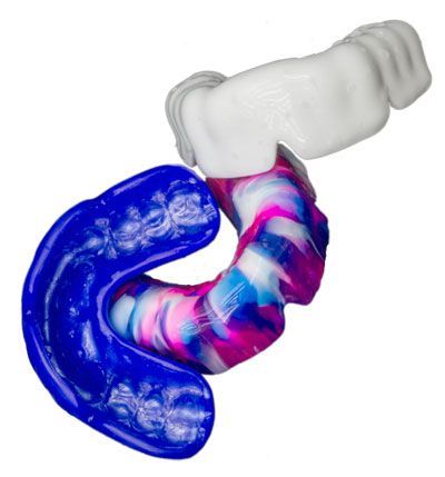 A Blue And Pink Mouth Guard Is Sitting On A White Surface — Cosmetic Denture Services–Jacob Maxwell in Mackay, QLD