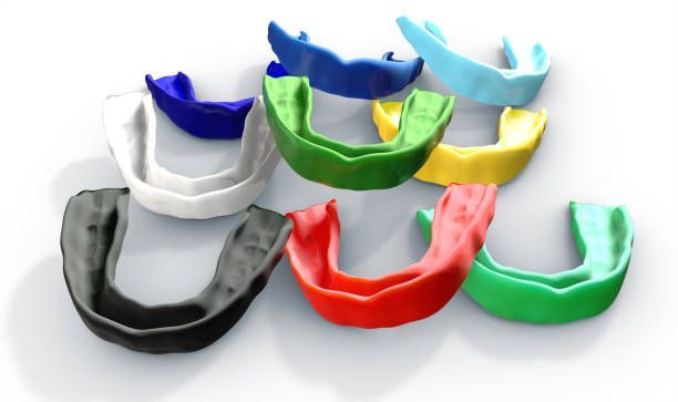 A Bunch Of Mouth Guards Of Different Colors On A White Surface — Cosmetic Denture Services–Jacob Maxwell in Mackay, QLD