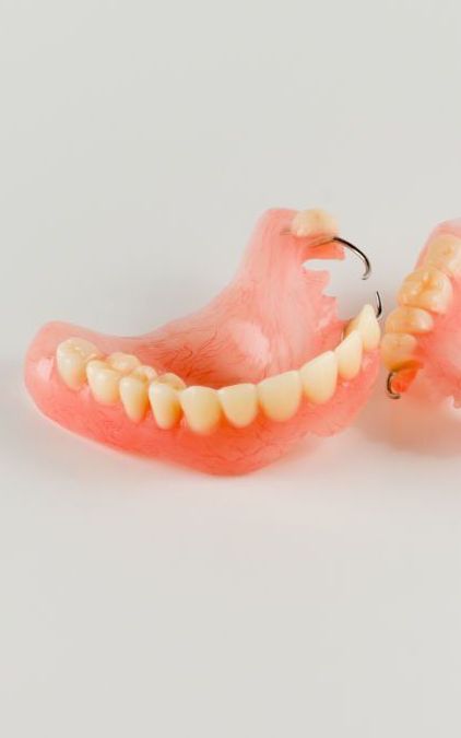 Pair of Dentures Are Sitting on a White Surface — Cosmetic Denture Services–Jacob Maxwell in Mackay, QLD