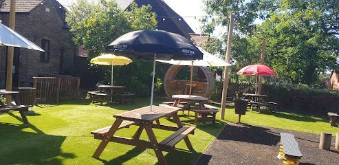 Sunny backyard with picnic tables, colorful umbrellas, and a wooden gazebo on a grassy patio