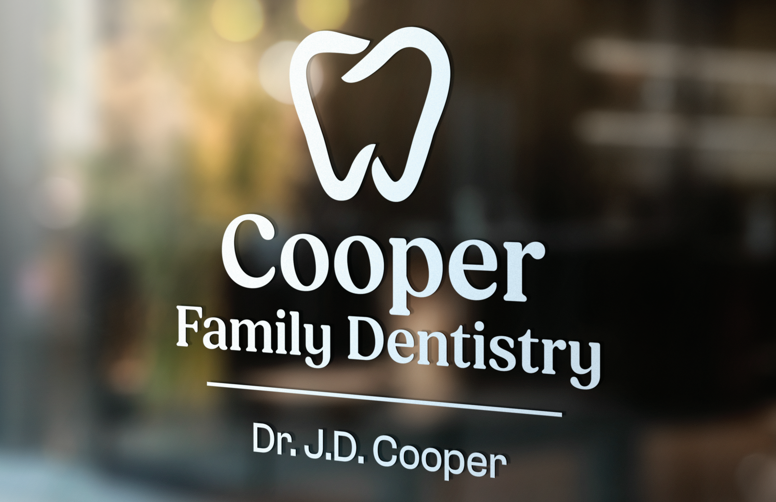 Cooper Family Dentistry sign with white tooth logo and Dr. J.D. Cooper name on blurred background