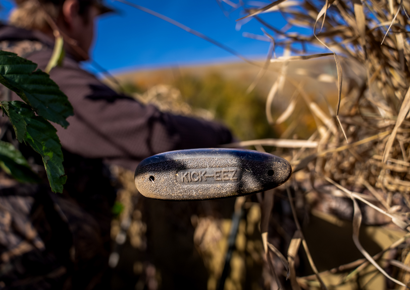 Close-up of a black Kenda bicycle pedal with dry grass and a blue sky in the background