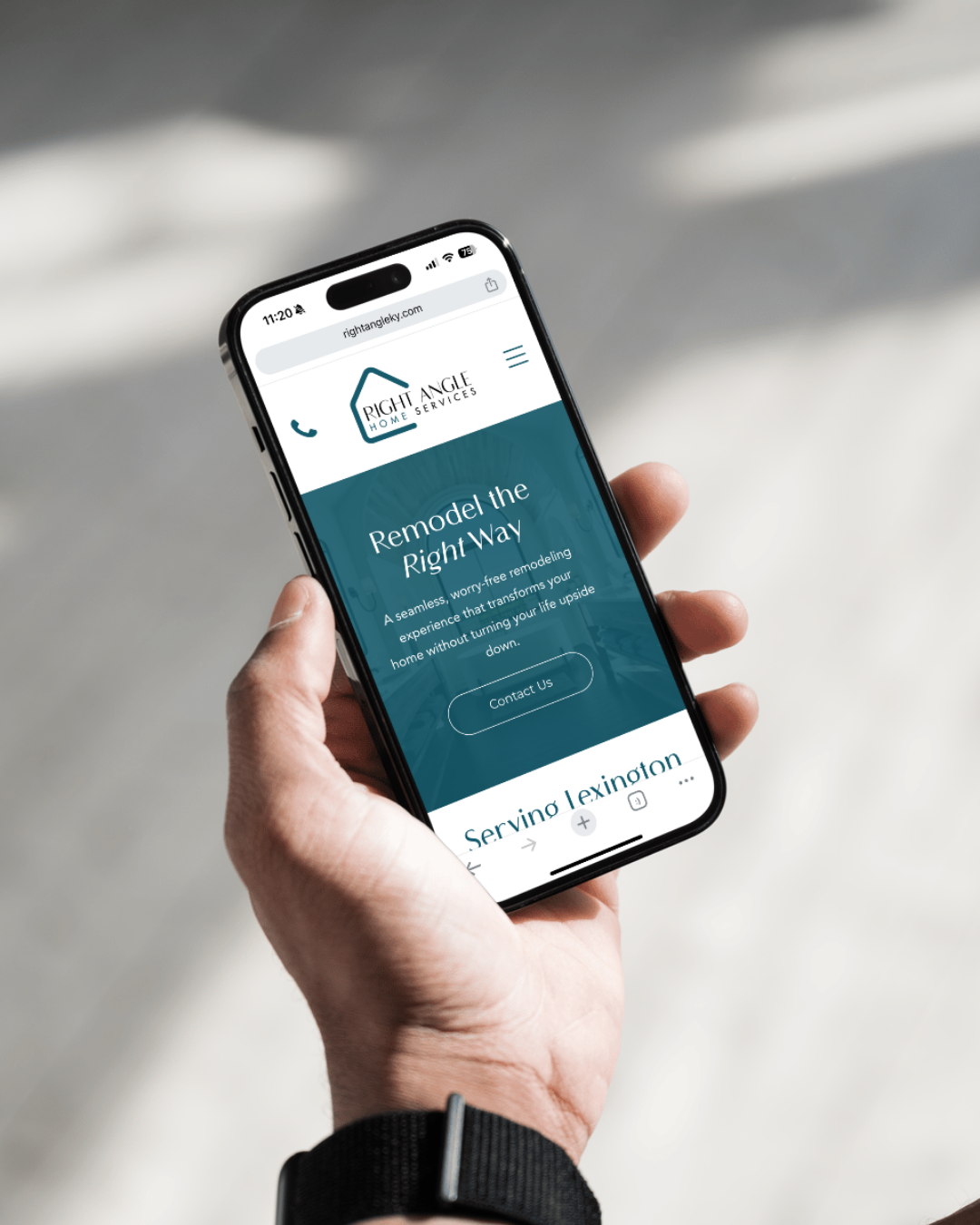 Hand holding smartphone showing a teal app screen on a bright blurred background