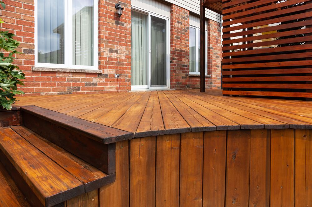 A wooden deck with stairs and a brick house in the background — Port Stephens Bathrooms In New Lambton, NSW