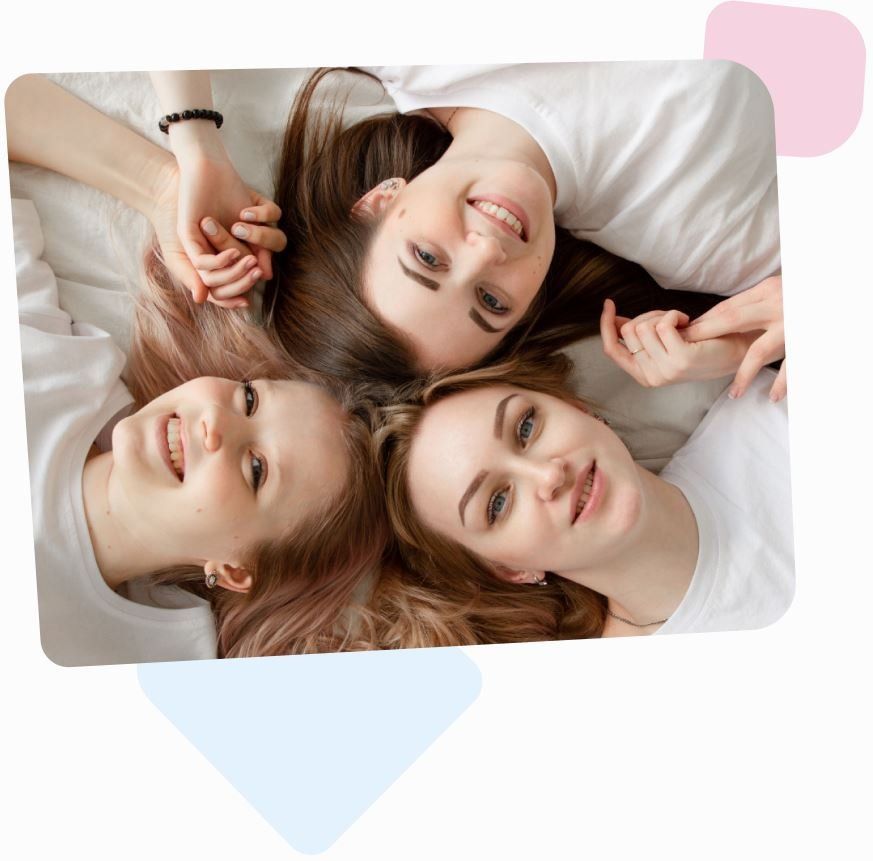 three young happy female egg donors smiling and holding hands