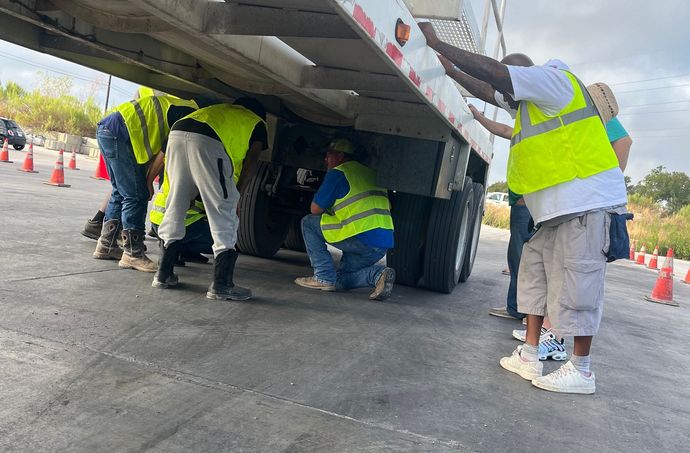 A group of men are standing in front of a semi truck getting their CDL