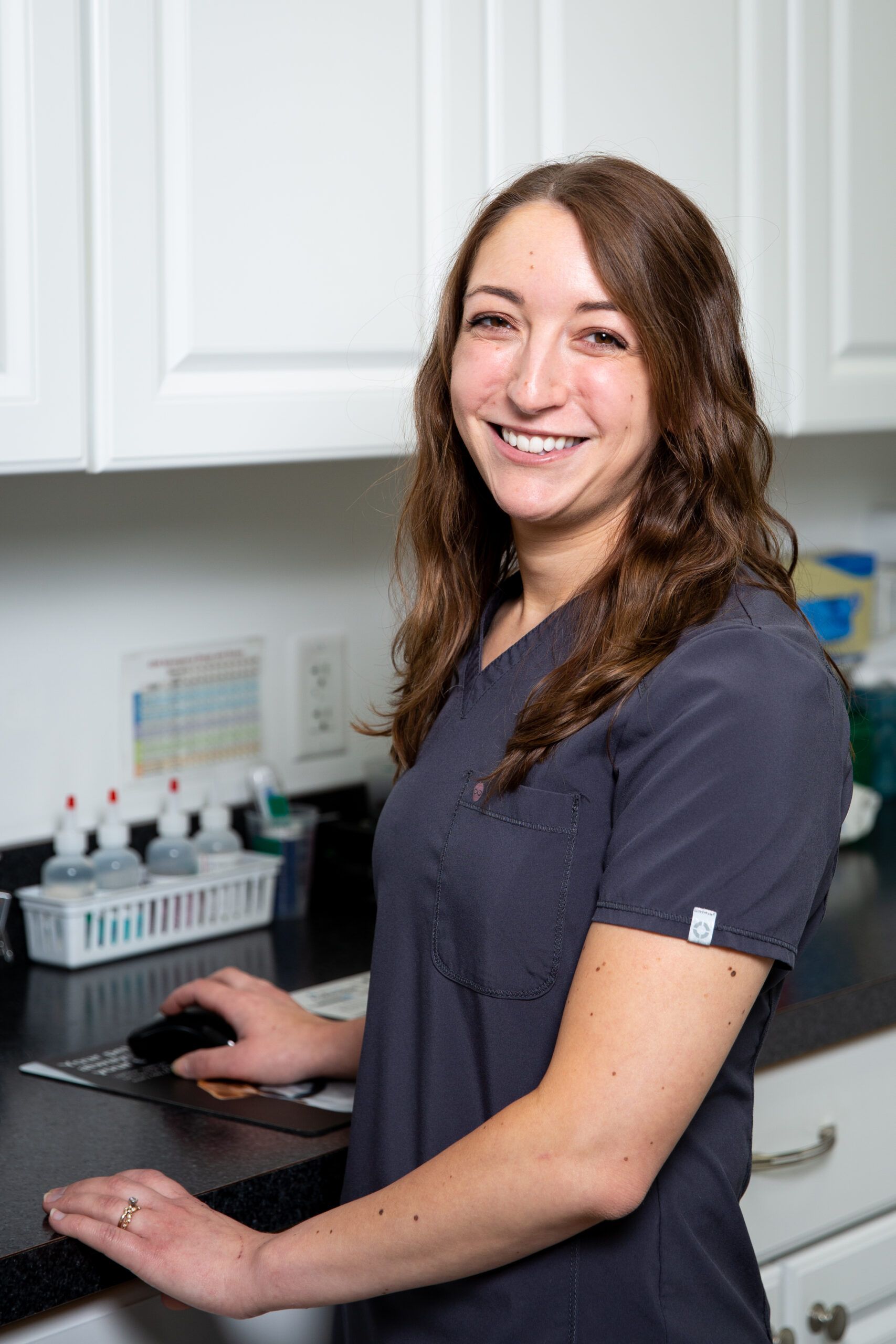 A woman in a scrub top is standing in front of a counter in a kitchen.