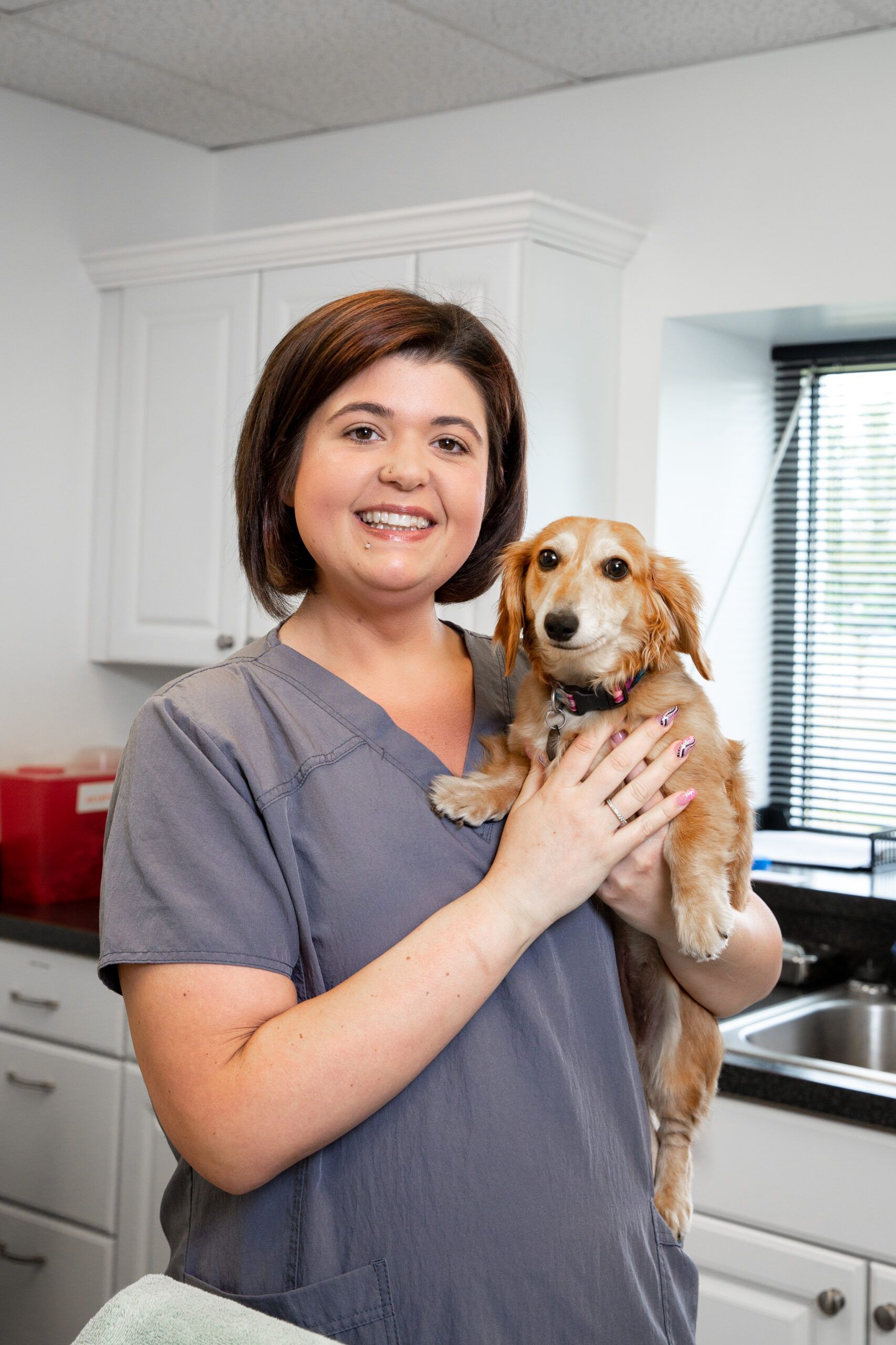 A woman is holding a puppy in her arms in a veterinary office.