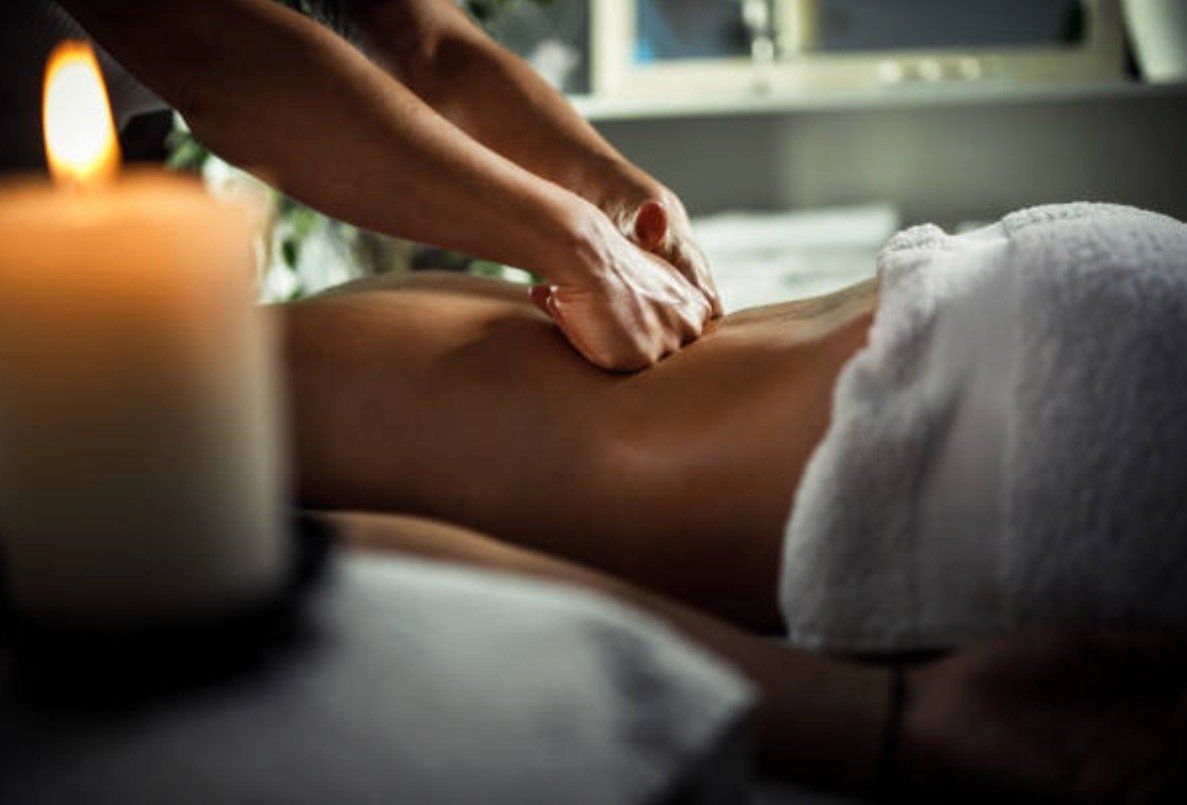 A woman is getting a massage in a spa with a candle in the background.