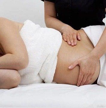 A pregnant woman is getting a massage from a massage therapist