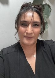 A woman wearing glasses and red lipstick is smiling in a car.