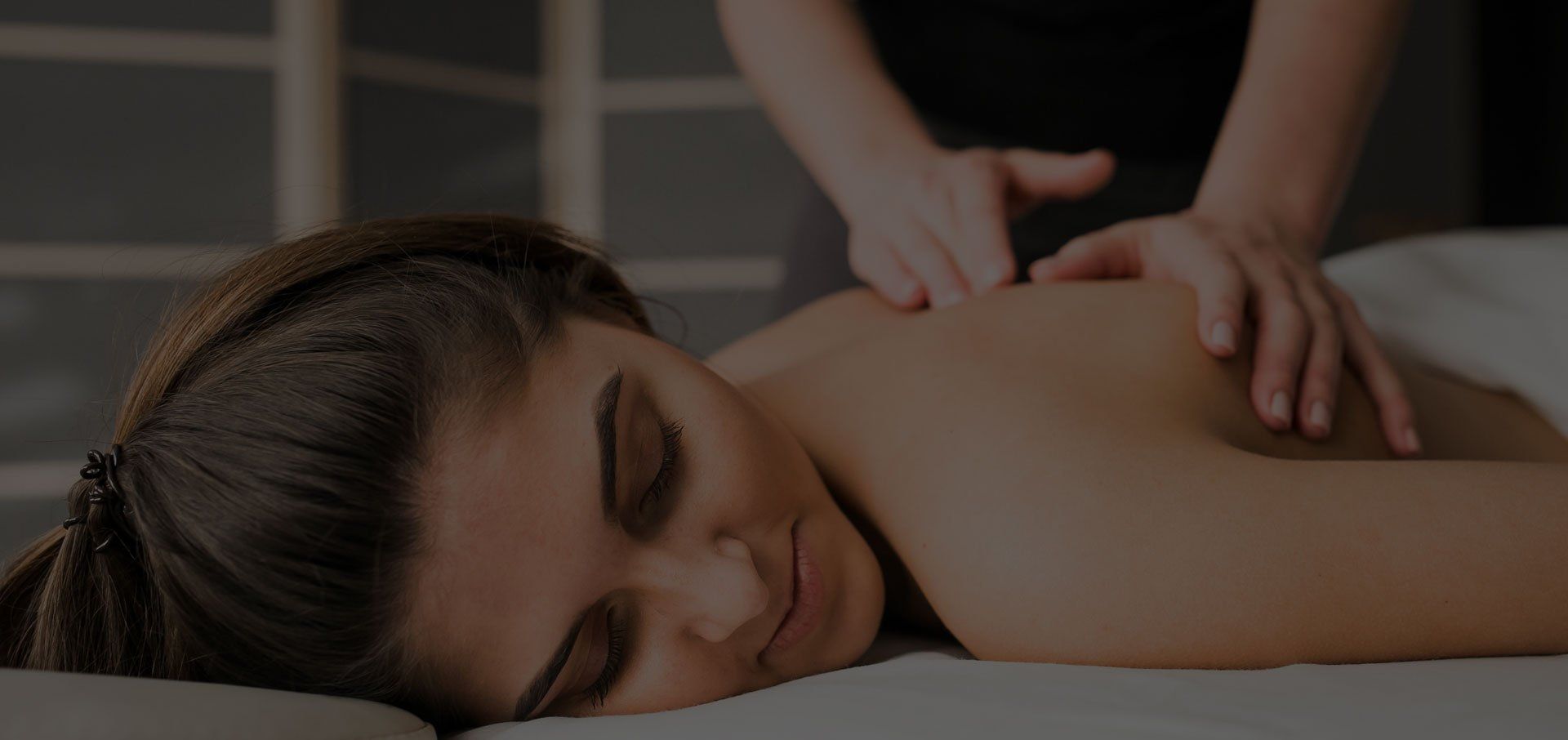A woman is laying on a bed getting a massage.
