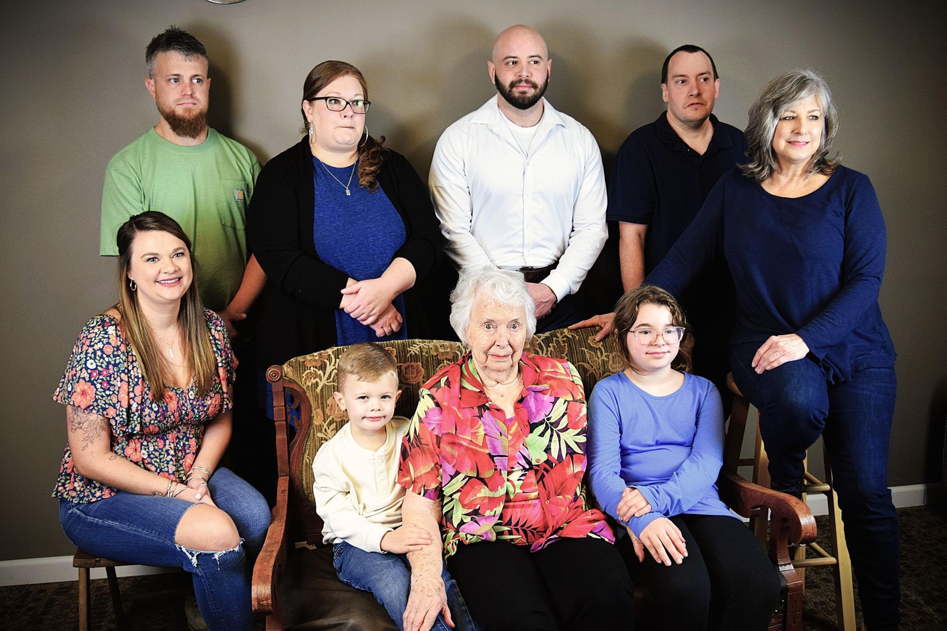 Family portrait: Nine people pose together indoors, smiling.
