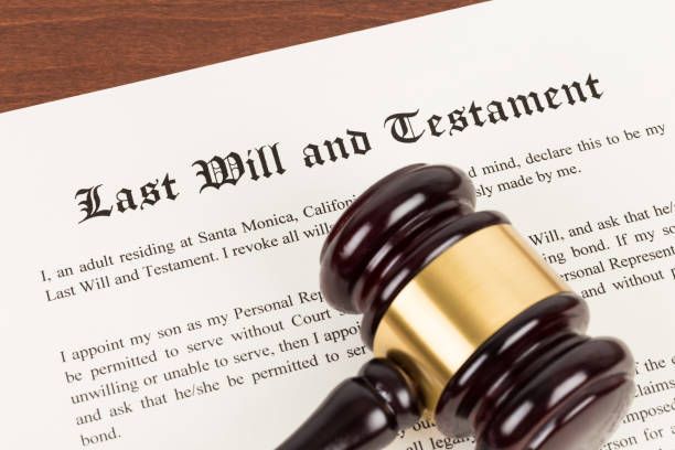 Last will and testament on paper with wooden judge gavel lying on top.