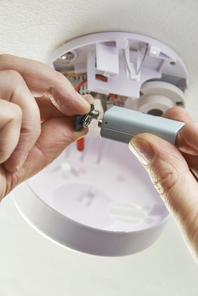 A Person Is Removing A Battery From A Smoke Detector — Cool & Secure In Warana, QLD