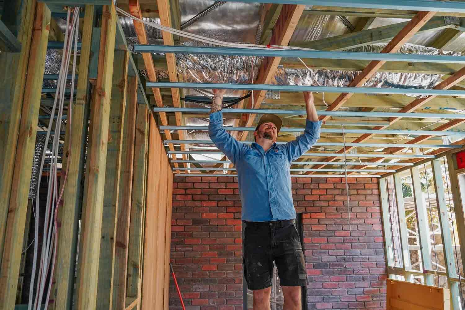A Man Is Working On The Ceiling Of A House Under Construction — Cool & Secure In Warana, QLD