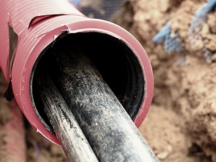 A Close Up Of A Red And Black Pipe In The Dirt — Cool & Secure In Maroochydore, QLD