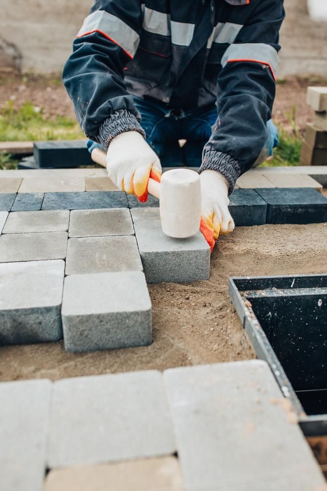 A Man is Laying Bricks With a Rubber Mallet — Lennox Build In Bangalow, NSW