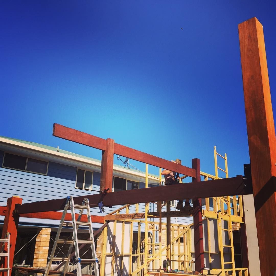 A man is sitting on wooden frame of new build while in the sun — Lennox Build In Lennox Head, NSW