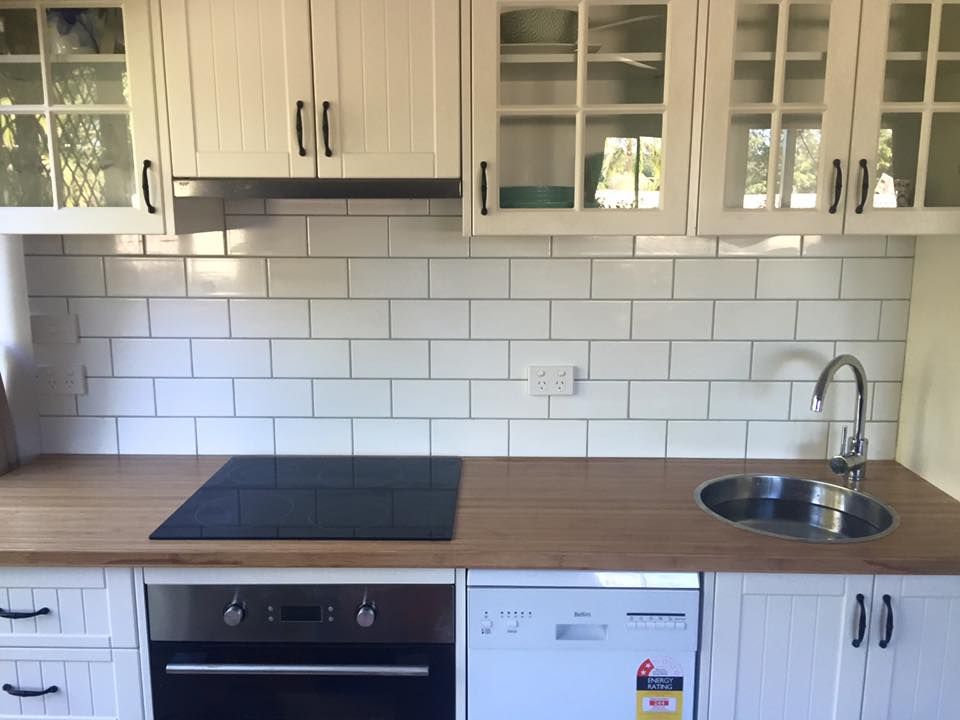 A Kitchen With White Cabinets and a Black Stove Top Oven — Lennox Build In Lennox Head, NSW