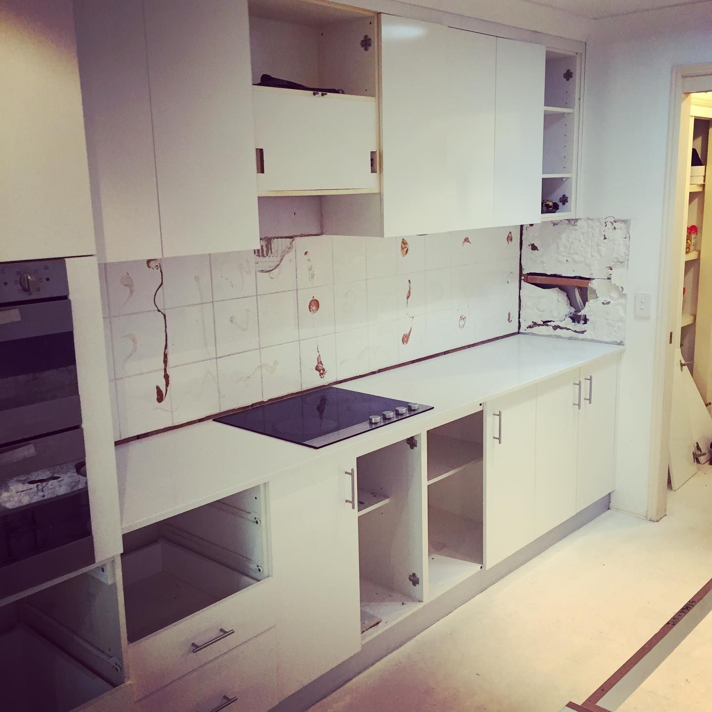 A Kitchen With White Cabinets and a Stove Top Oven — Lennox Build In Lennox Head, NSW