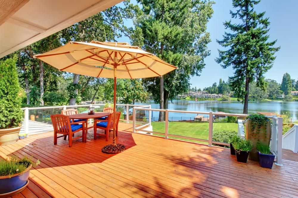 A Wooden Deck With a Table and Chairs and an Umbrella Overlooking a Lake — Lennox Build In Alstonville, NSW
