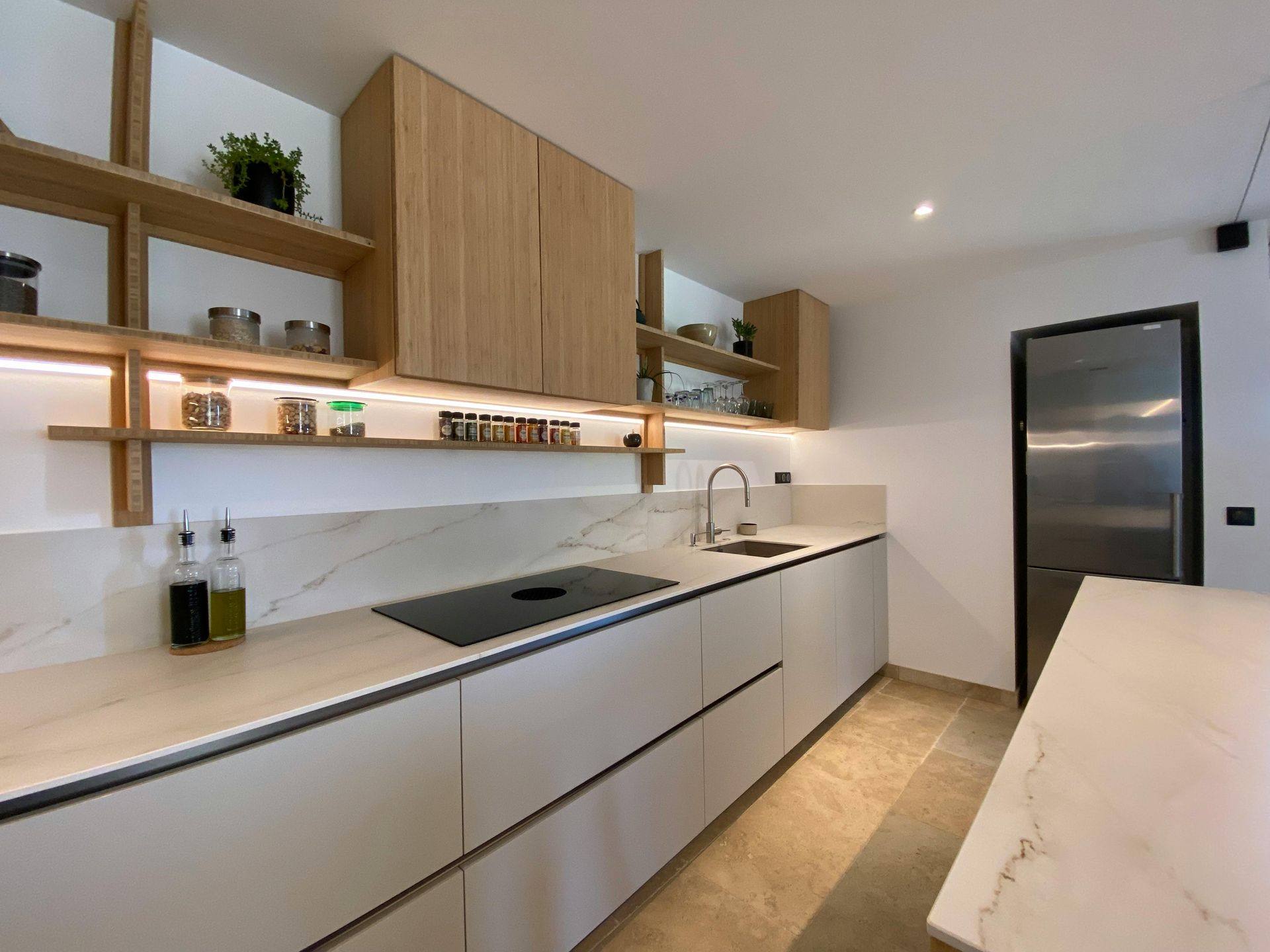 Modern kitchen with light wood cabinets, white countertops, and stainless steel appliances.